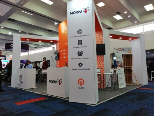 Stand modular blanco con pilares altos de Morwi y Magento, ideal para ferias de servicios digitales y consultoría.