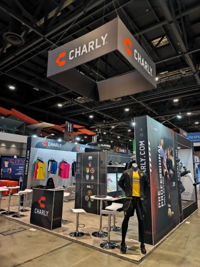 Stand modular de gran formato para la marca Charly con estructuras colgantes, maniquíes y racks de ropa deportiva.