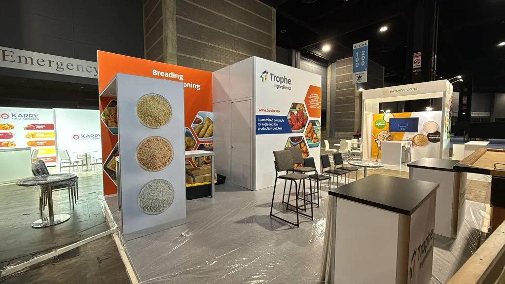Stand ecológico de Trophe Ingredients con gráficos de pan molido y acabados sustentables en una feria de alimentos.