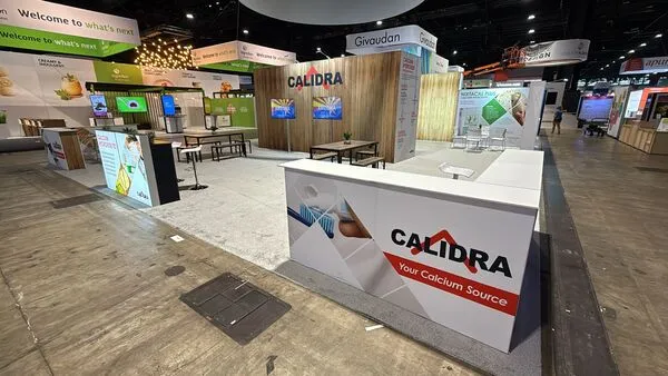 Gran stand de feria comercial con acabados de madera y mostradores que exhiben la identidad de marca de Calidra.