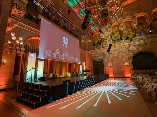 Vista lateral de escenario iluminado con tótems de publicidad gráfica para galas